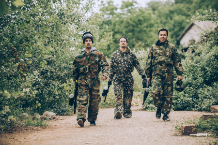 three paintball players in camo walking through forest