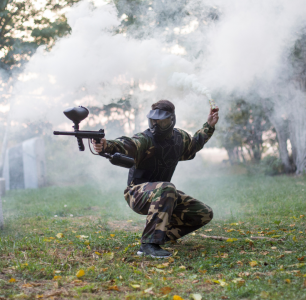 paintball player crouched in smoke shooting marker